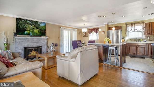 living room featuring sink, a fireplace, light hardwood / wood-style floors, and a healthy amount of sunlight