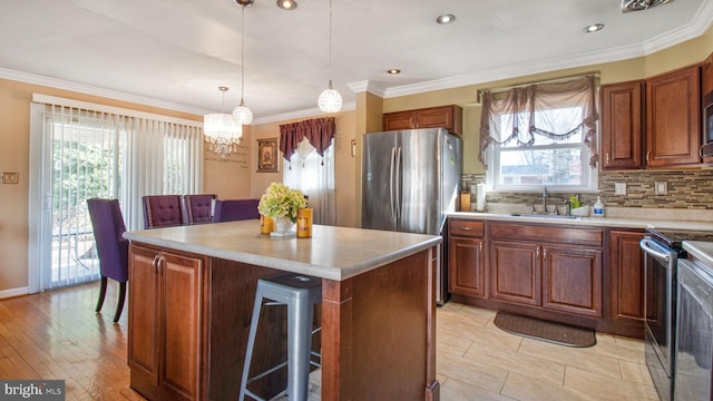 kitchen featuring sink, backsplash, stainless steel appliances, a center island, and decorative light fixtures