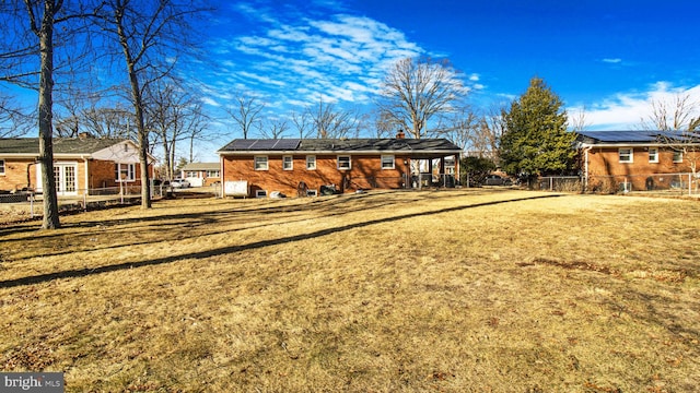 back of house with a lawn and solar panels