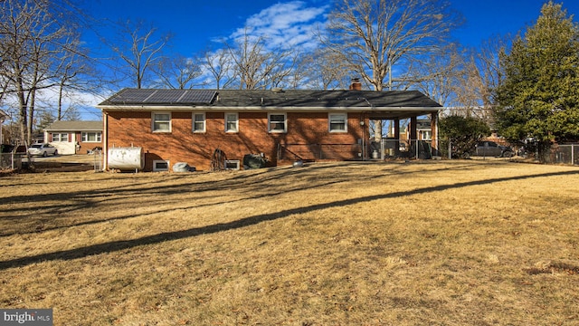 back of property with a lawn and solar panels