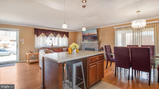 kitchen featuring ornamental molding, a brick fireplace, a center island, and pendant lighting