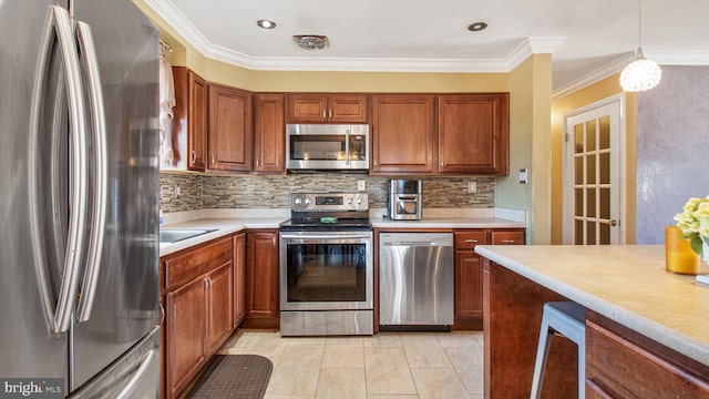 kitchen with ornamental molding, appliances with stainless steel finishes, pendant lighting, and backsplash