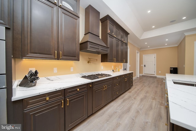 kitchen featuring stainless steel gas cooktop, dark brown cabinets, ornamental molding, custom exhaust hood, and glass insert cabinets