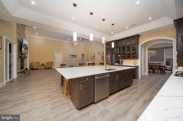 kitchen with a spacious island, hanging light fixtures, stainless steel dishwasher, glass insert cabinets, and dark brown cabinetry