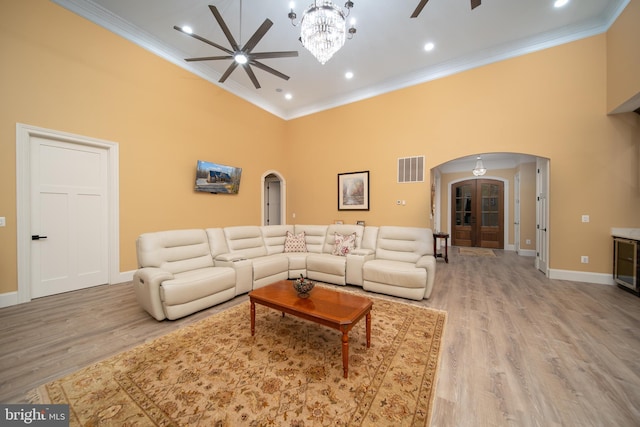 living area with visible vents, arched walkways, a ceiling fan, a towering ceiling, and ornamental molding