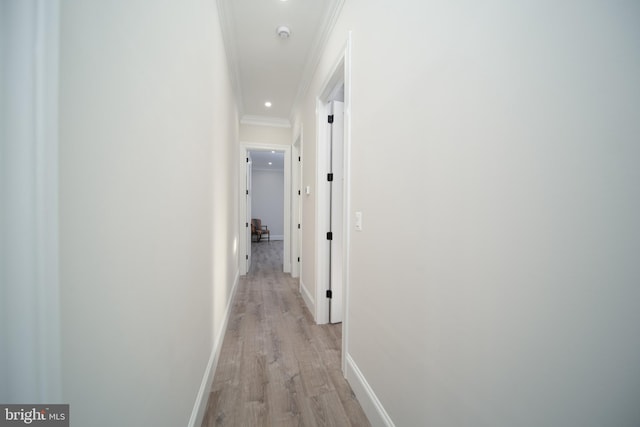 hallway with light wood-style floors, recessed lighting, crown molding, and baseboards