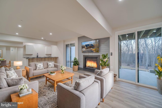 living area with a large fireplace, light wood finished floors, plenty of natural light, and recessed lighting