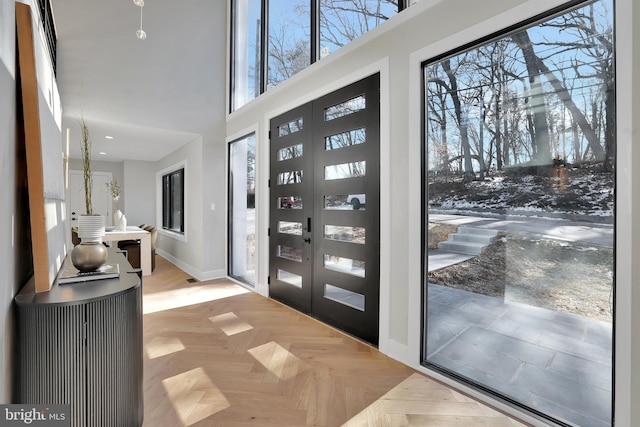 foyer entrance with light parquet flooring and a towering ceiling