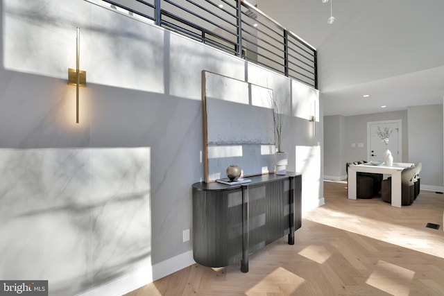 interior space with light parquet flooring and a towering ceiling