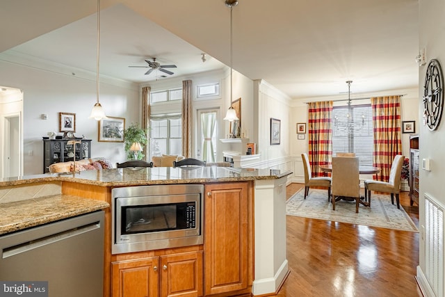 kitchen featuring pendant lighting, crown molding, stainless steel appliances, and light wood-type flooring