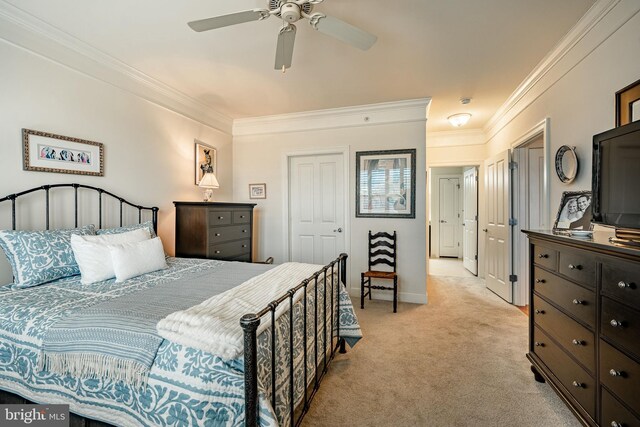 carpeted bedroom with ceiling fan, ornamental molding, and a closet