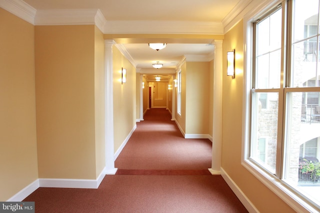 hall with ornamental molding, decorative columns, and carpet