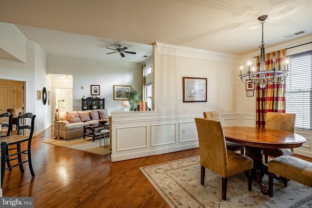 dining space with crown molding, ceiling fan with notable chandelier, and hardwood / wood-style floors