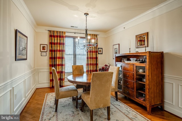 dining room with hardwood / wood-style flooring, crown molding, and a notable chandelier