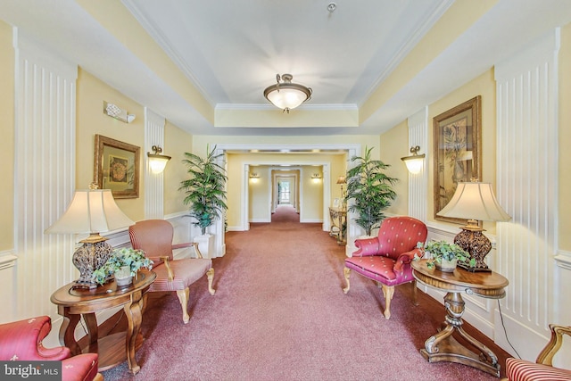 sitting room featuring ornamental molding, a raised ceiling, and carpet flooring