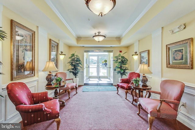 living area with crown molding, a tray ceiling, and carpet flooring