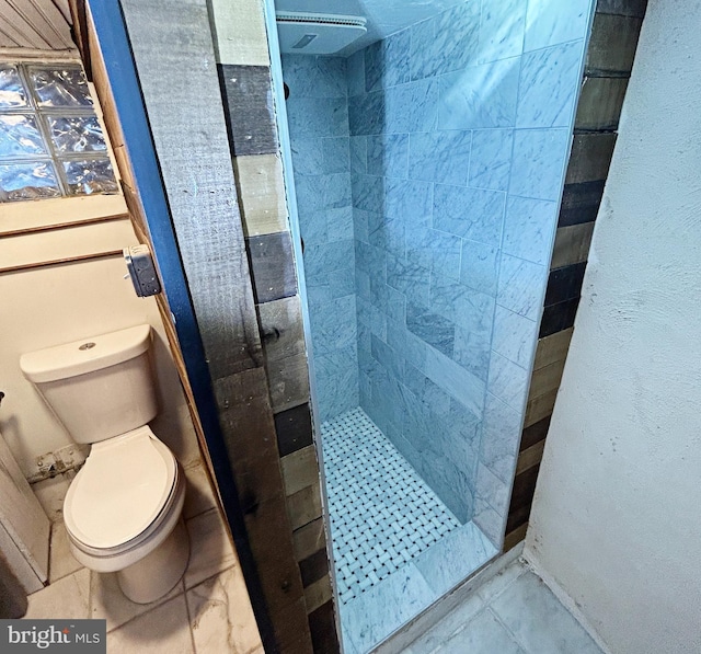 bathroom featuring tiled shower and toilet