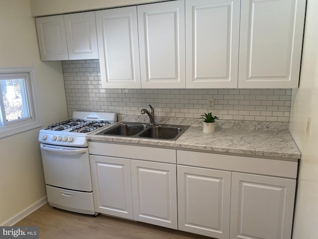 kitchen with white cabinetry, sink, backsplash, white range with gas cooktop, and light hardwood / wood-style floors