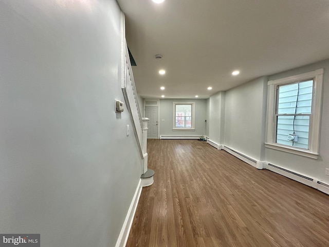 basement featuring a baseboard radiator and hardwood / wood-style floors