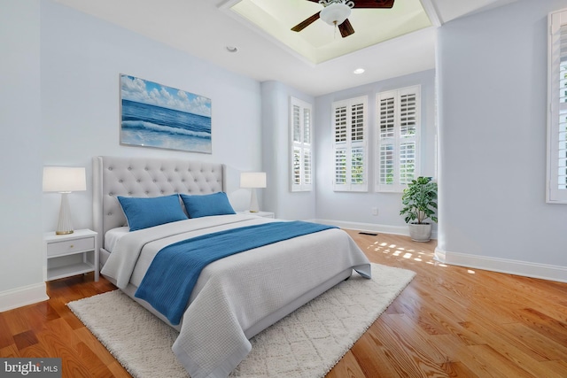 bedroom featuring a tray ceiling, wood-type flooring, and ceiling fan