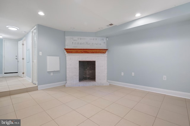 unfurnished living room with light tile patterned flooring and a brick fireplace