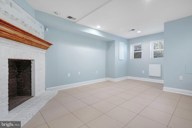 unfurnished living room with a brick fireplace and light tile patterned floors