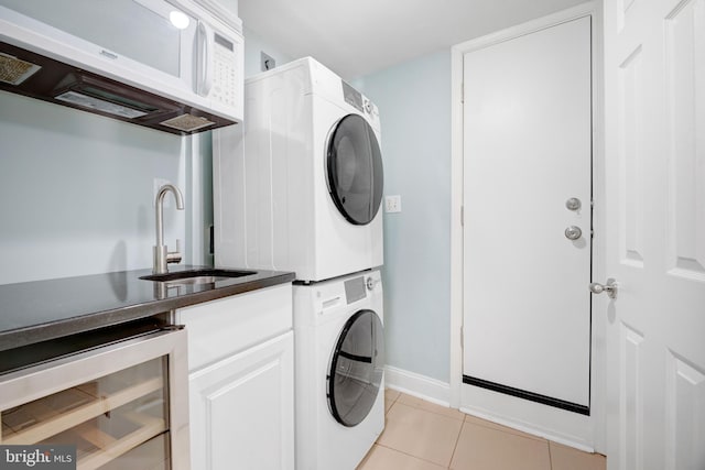 laundry room with sink, wine cooler, cabinets, stacked washer and clothes dryer, and light tile patterned floors