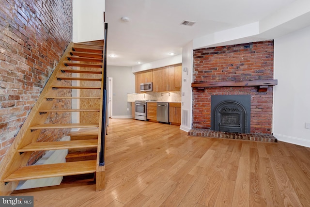 stairway featuring brick wall and wood-type flooring