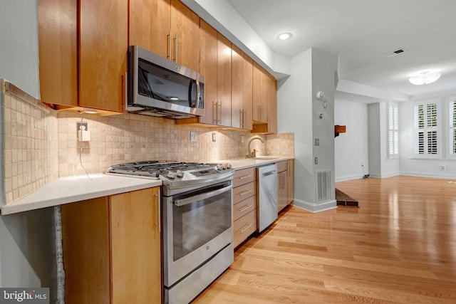 kitchen featuring tasteful backsplash, appliances with stainless steel finishes, sink, and light hardwood / wood-style floors