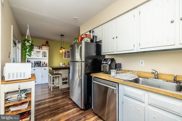 kitchen with pendant lighting, appliances with stainless steel finishes, sink, and white cabinets