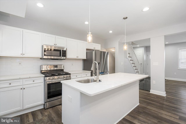 kitchen with pendant lighting, sink, a kitchen island with sink, white cabinetry, and stainless steel appliances