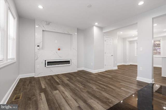 unfurnished living room with dark wood-type flooring and a high end fireplace