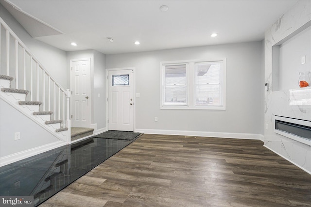 foyer entrance featuring dark wood-type flooring and a high end fireplace