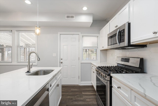 kitchen featuring white cabinetry, sink, stainless steel appliances, and hanging light fixtures