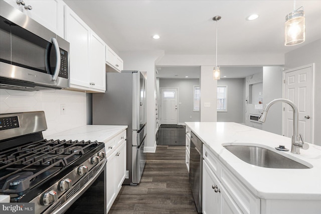 kitchen with sink, white cabinetry, a center island with sink, pendant lighting, and stainless steel appliances