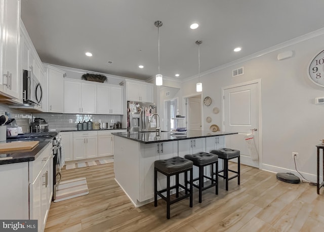 kitchen featuring white cabinetry, stainless steel appliances, and an island with sink