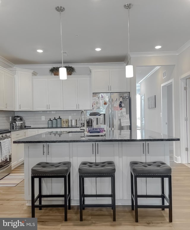 kitchen with decorative light fixtures, an island with sink, and appliances with stainless steel finishes