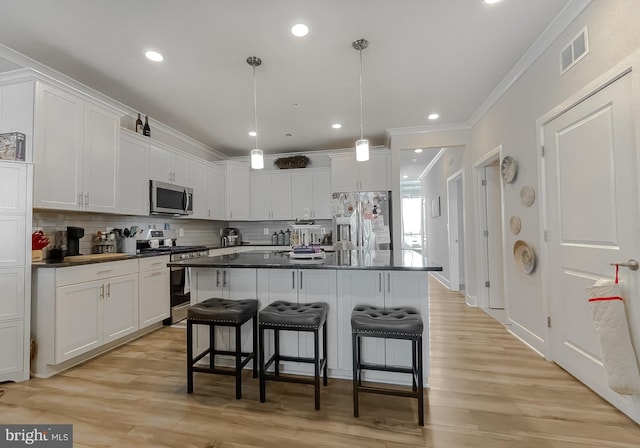 kitchen with appliances with stainless steel finishes, white cabinets, and decorative light fixtures