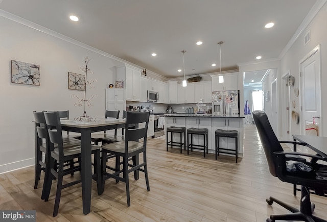 dining area with ornamental molding and light hardwood / wood-style flooring