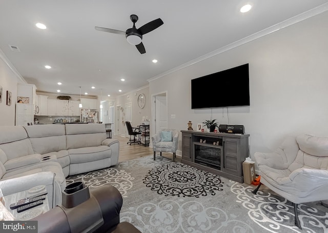 living room featuring crown molding, ceiling fan, and light hardwood / wood-style floors