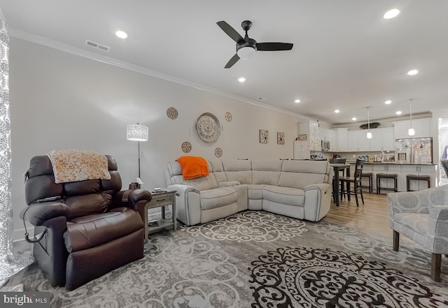 living room featuring crown molding, ceiling fan, and light hardwood / wood-style flooring