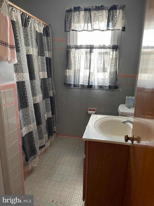 bathroom with tile walls, vanity, tile patterned flooring, and toilet