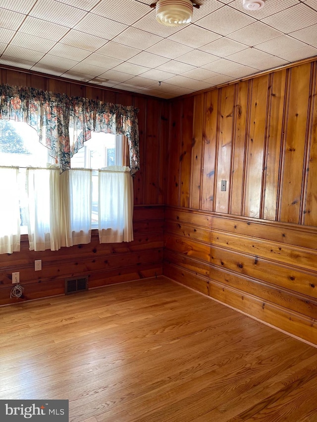 spare room with wooden walls and light wood-type flooring