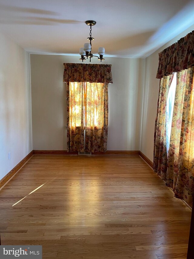 unfurnished room with hardwood / wood-style floors and a chandelier