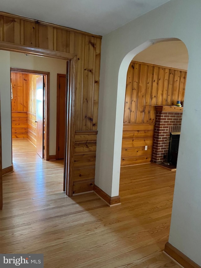 corridor featuring light wood-type flooring and wood walls