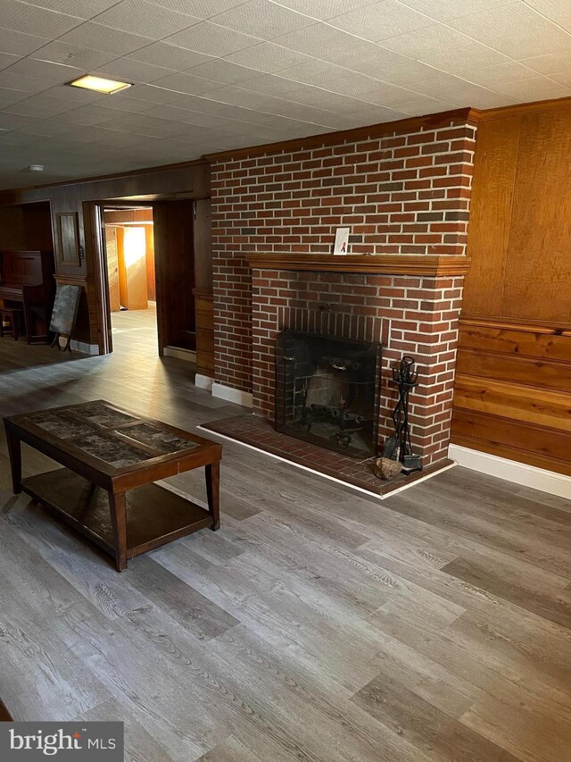 unfurnished living room with a brick fireplace, wood-type flooring, and wooden walls