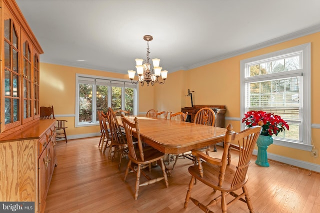 dining space featuring crown molding, a chandelier, and light wood-type flooring