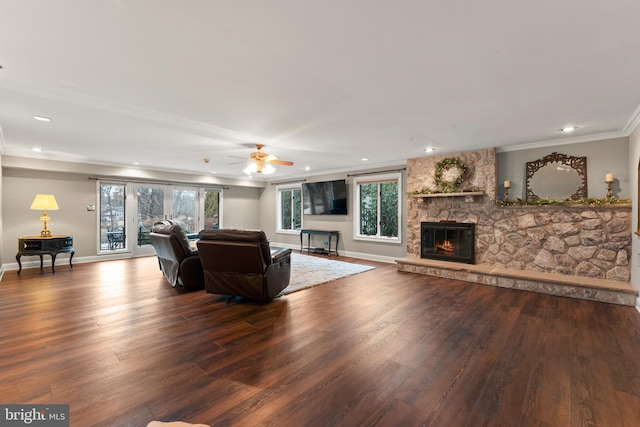 living room with ornamental molding, a stone fireplace, dark hardwood / wood-style floors, and ceiling fan