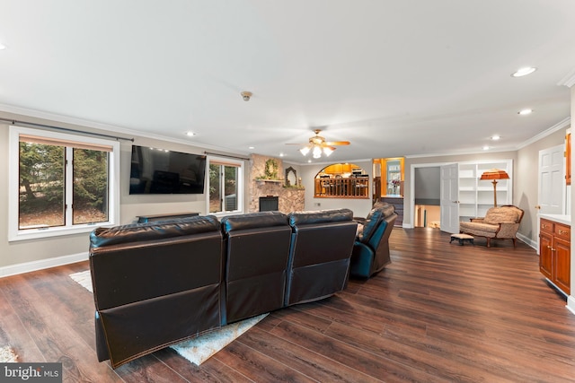 living room featuring ornamental molding, a stone fireplace, dark hardwood / wood-style floors, and ceiling fan