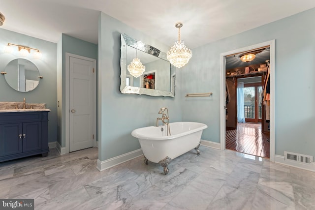 bathroom featuring vanity, a bathtub, and a chandelier